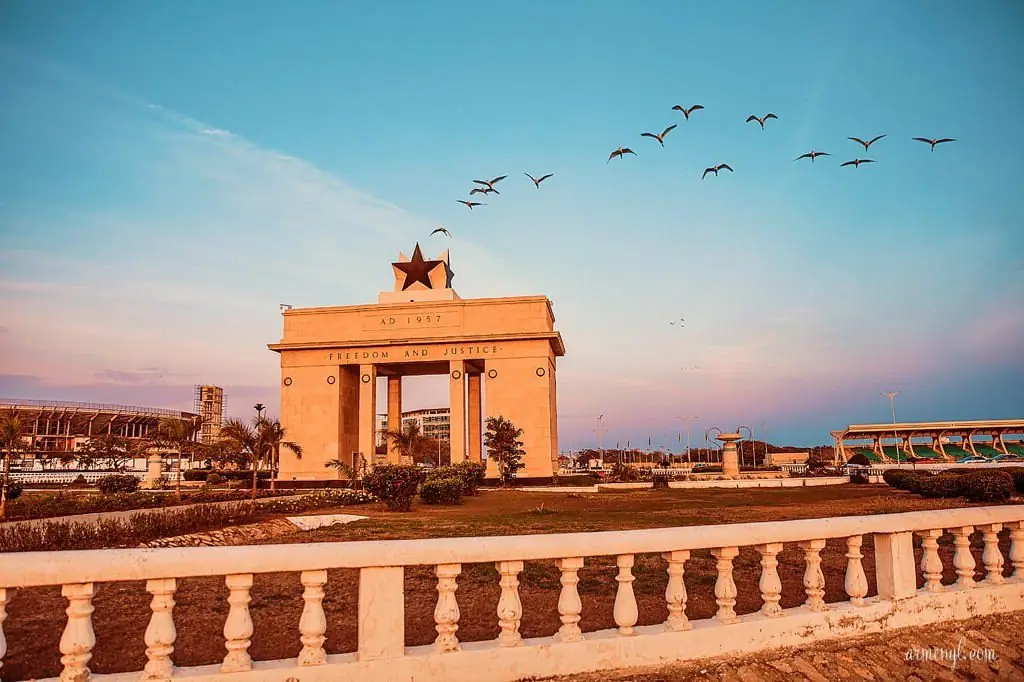 The Black Star Gate in Accra at dusk, birds crossing the sky.